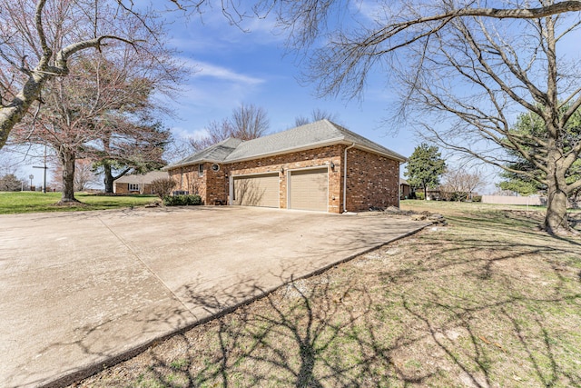 view of home's exterior featuring driveway, a yard, an attached garage, a shingled roof, and brick siding