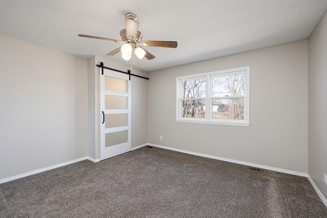 empty room with a textured ceiling, baseboards, and dark colored carpet