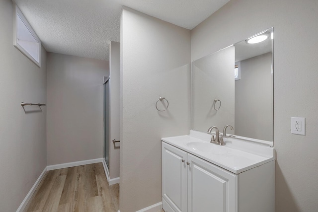 bathroom featuring vanity, wood finished floors, baseboards, and a stall shower