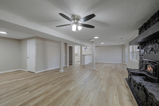 living area with baseboards, a textured ceiling, a ceiling fan, and light wood finished floors