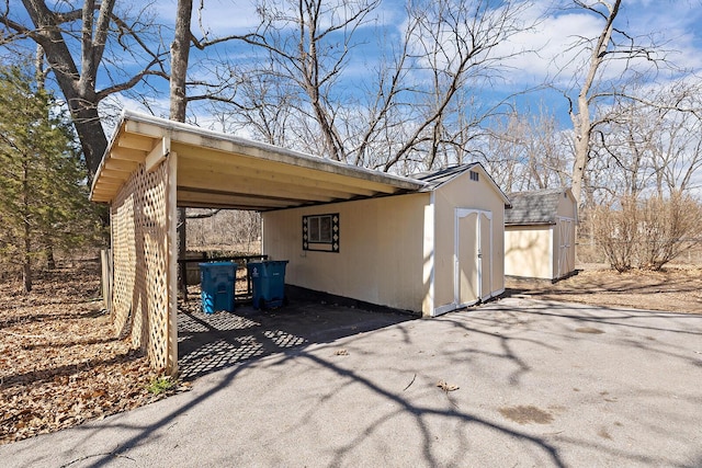 view of shed featuring an attached carport and aphalt driveway