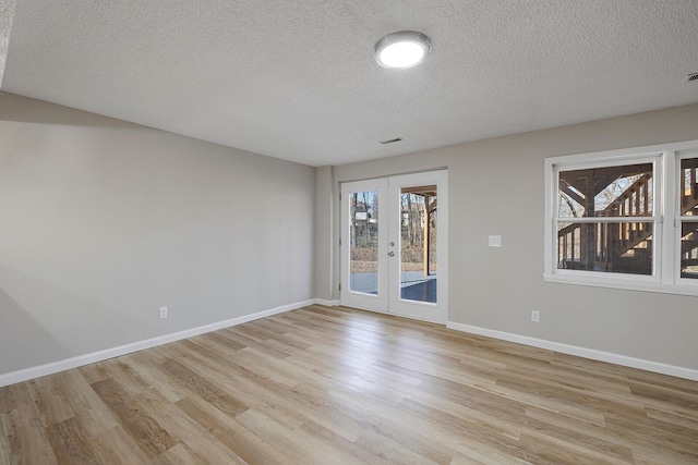 spare room featuring light wood-style floors, french doors, visible vents, and baseboards