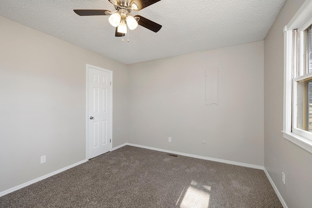 unfurnished room featuring a textured ceiling, baseboards, a ceiling fan, and dark colored carpet