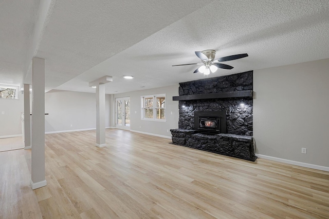 unfurnished living room with ceiling fan, a textured ceiling, baseboards, and wood finished floors