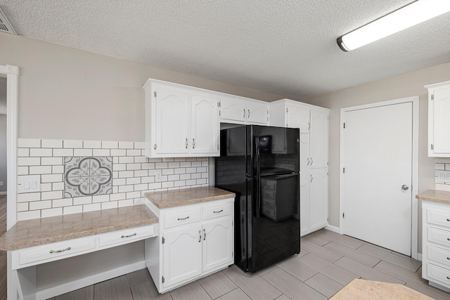 kitchen with backsplash, white cabinets, light countertops, and freestanding refrigerator