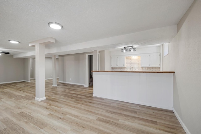 interior space with light wood-style flooring, baseboards, and a textured ceiling