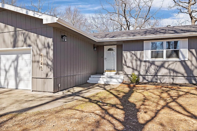 doorway to property featuring a garage and a shingled roof