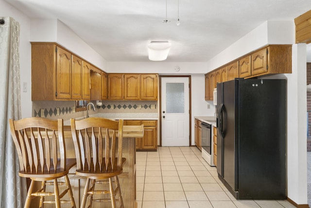 kitchen featuring a peninsula, a kitchen breakfast bar, electric stove, brown cabinetry, and black fridge with ice dispenser