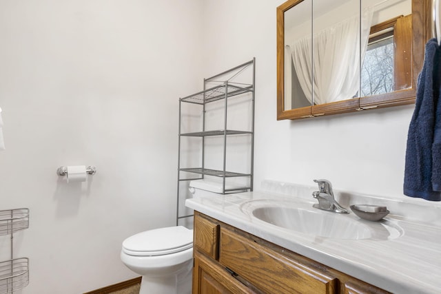 bathroom with toilet, vanity, and baseboards