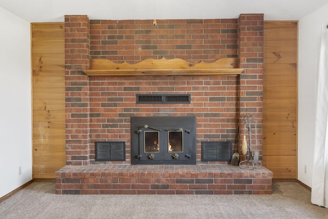 room details with carpet flooring, wood walls, a fireplace, and visible vents