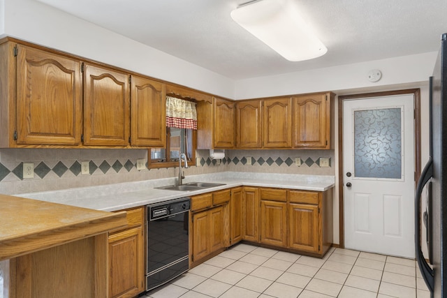 kitchen with dishwasher, light countertops, brown cabinetry, and a sink