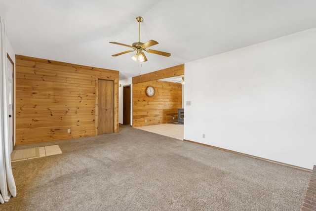 carpeted empty room with wood walls, baseboards, and a ceiling fan