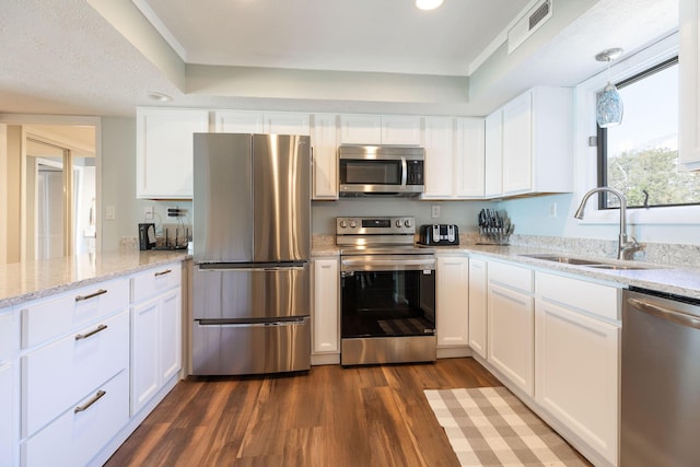 kitchen featuring white cabinets, appliances with stainless steel finishes, dark wood-type flooring, and a sink