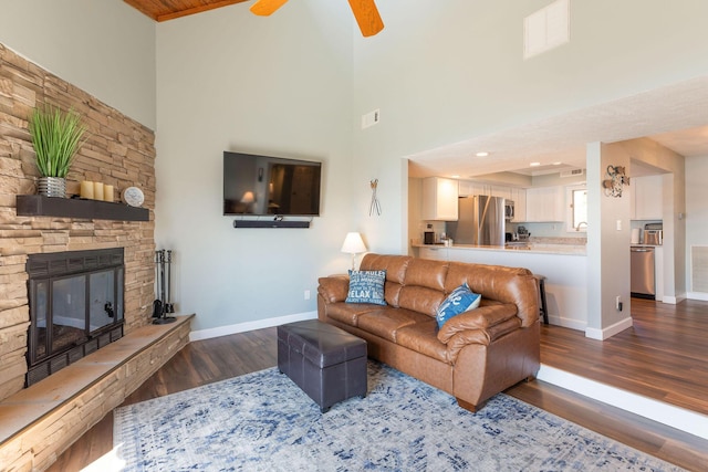 living room with visible vents, baseboards, wood finished floors, and a ceiling fan