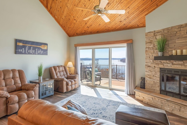 living room featuring ceiling fan, wood ceiling, wood finished floors, and a stone fireplace