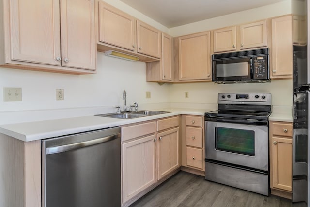 kitchen with light brown cabinets, light countertops, appliances with stainless steel finishes, wood finished floors, and a sink