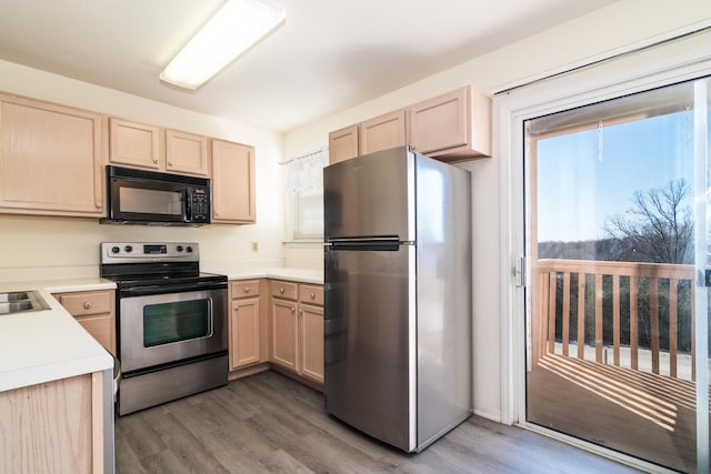 kitchen featuring light brown cabinetry, light countertops, appliances with stainless steel finishes, wood finished floors, and a sink