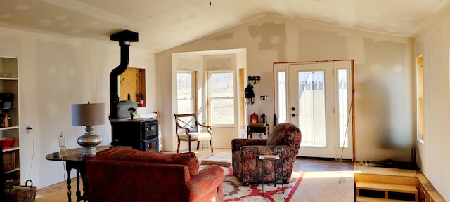 living room featuring wood finished floors, a wood stove, and vaulted ceiling