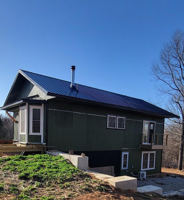 rear view of property featuring central AC and metal roof