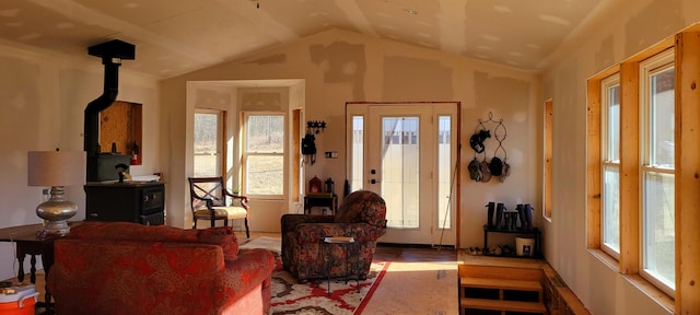 living area with vaulted ceiling, a wood stove, and wood finished floors