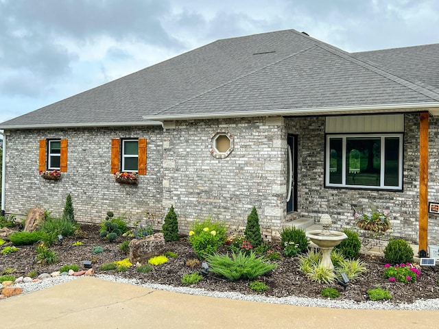 view of front of house featuring brick siding and roof with shingles