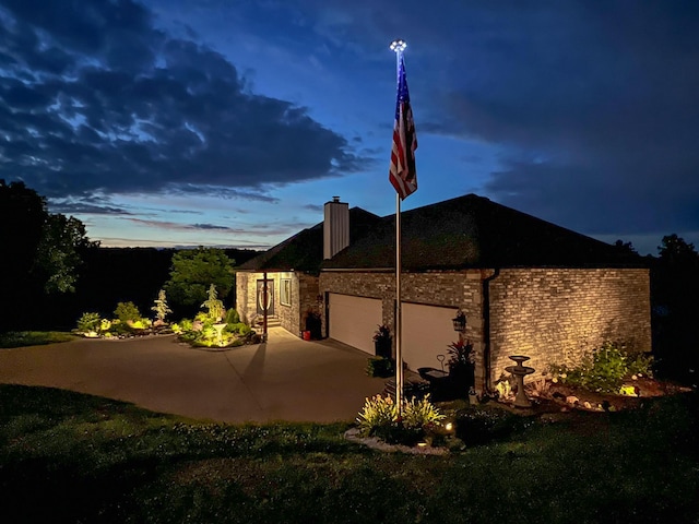 view of side of home with a patio, a garage, driveway, and a chimney