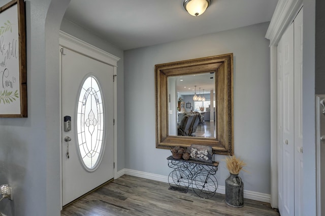 entryway featuring arched walkways, baseboards, and wood finished floors