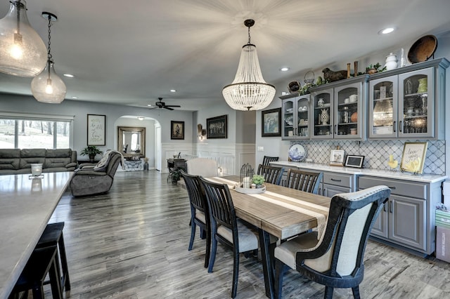 dining area featuring recessed lighting, light wood-type flooring, arched walkways, and ceiling fan with notable chandelier