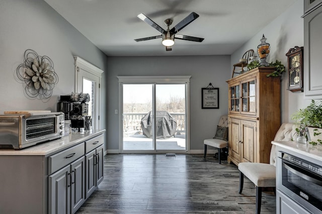 kitchen with a ceiling fan, dark wood-style floors, a toaster, gray cabinetry, and light countertops