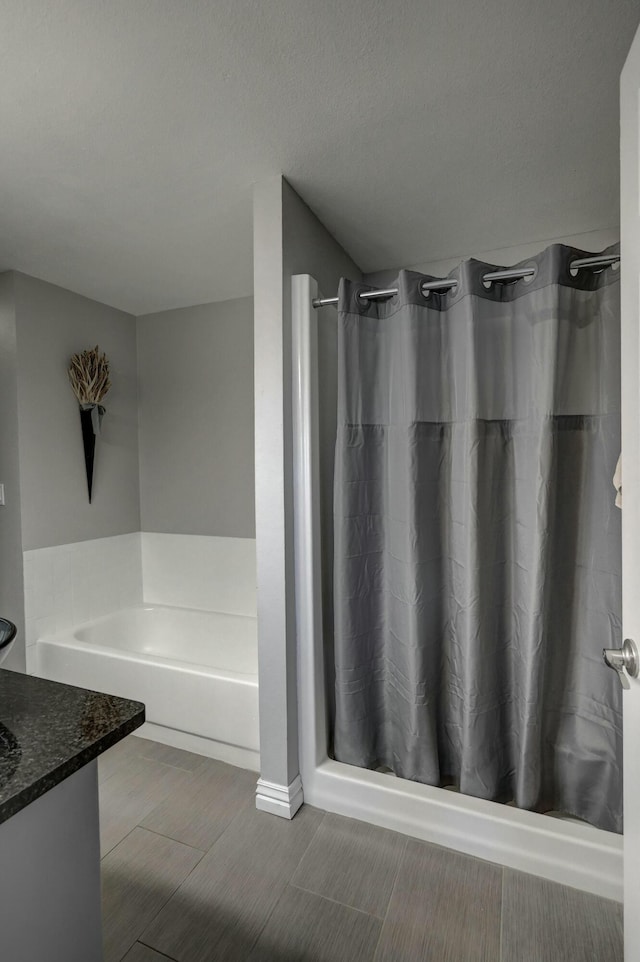 full bath with a stall shower, a textured ceiling, a bath, and vanity