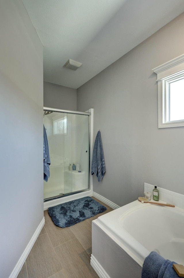 bathroom featuring visible vents, baseboards, a bath, and a shower stall