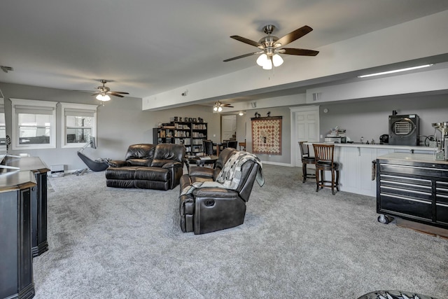 living area with visible vents, light carpet, baseboards, and a ceiling fan