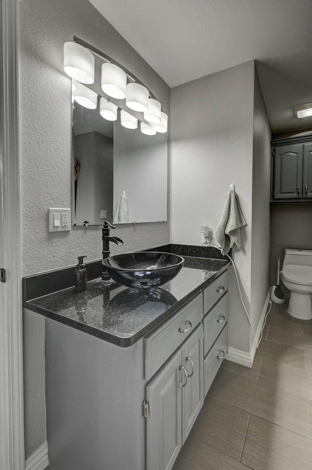 bathroom featuring baseboards, toilet, and vanity