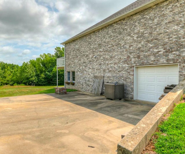 view of property exterior with central air condition unit, a lawn, a garage, a balcony, and brick siding