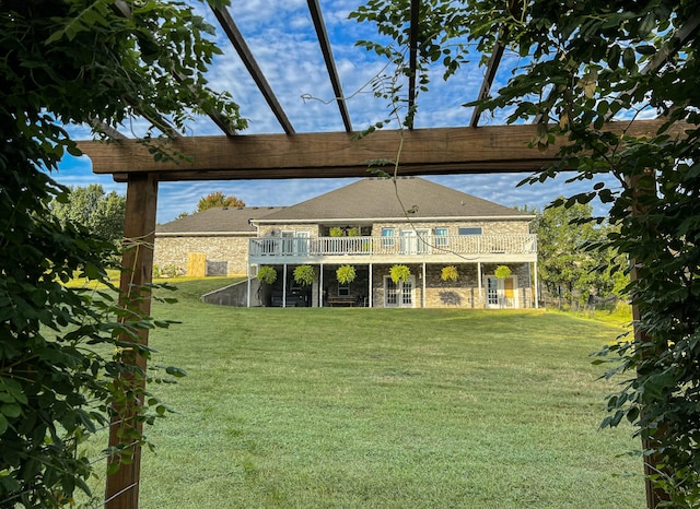 back of property with a deck, a yard, and stone siding