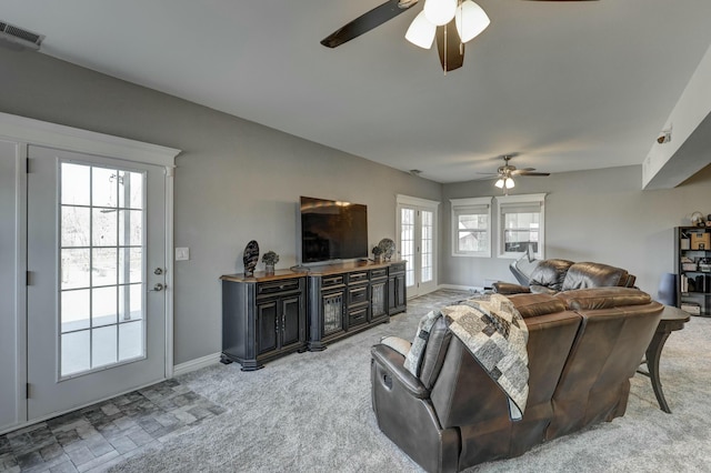 living area featuring light colored carpet, a ceiling fan, visible vents, and baseboards