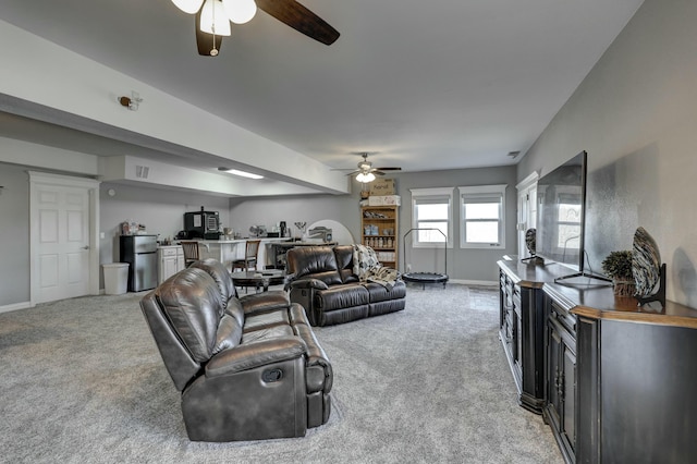 living area featuring a ceiling fan, light colored carpet, and baseboards