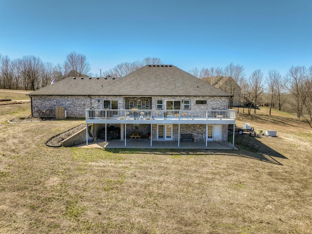 back of house with a patio, a lawn, stone siding, and a wooden deck