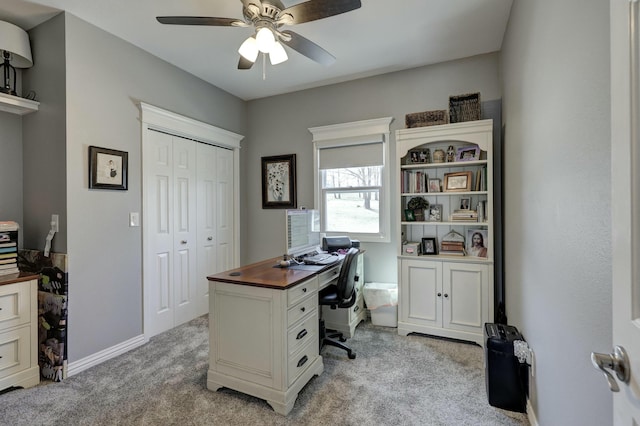 office area featuring light colored carpet, baseboards, and ceiling fan