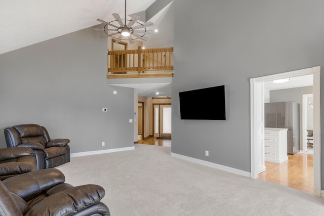 living area with baseboards, light carpet, high vaulted ceiling, and a ceiling fan