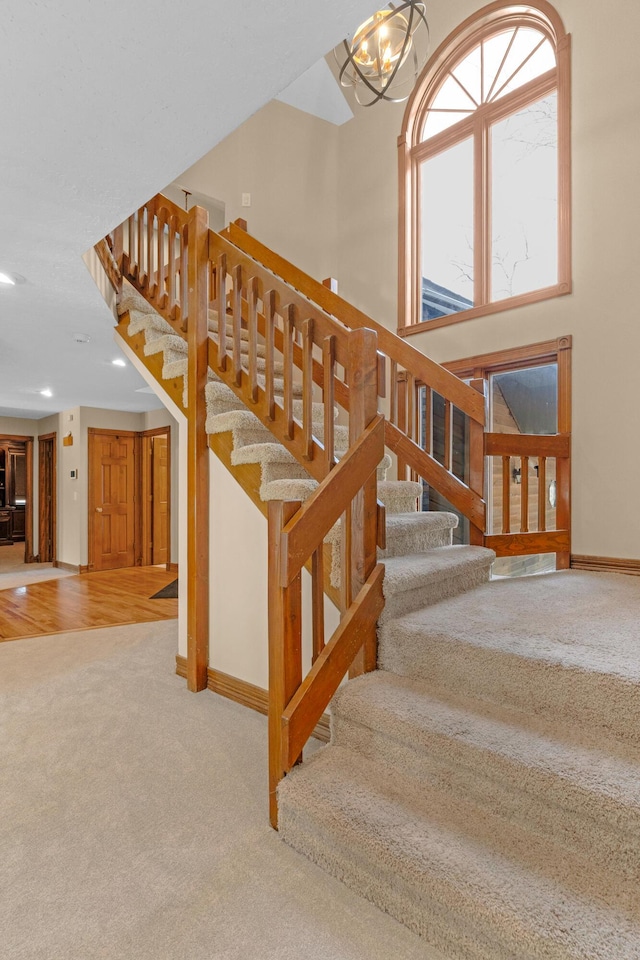 stairs featuring recessed lighting, a high ceiling, an inviting chandelier, carpet flooring, and baseboards