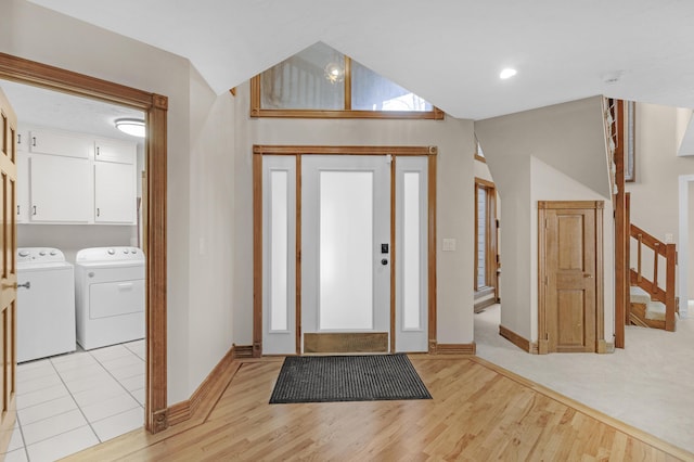 foyer entrance with baseboards, washing machine and clothes dryer, lofted ceiling, light wood-style flooring, and stairs