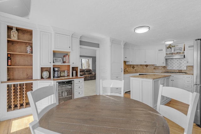 kitchen with beverage cooler, open shelves, backsplash, white cabinetry, and light wood-style floors