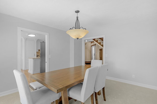 dining space featuring baseboards and light colored carpet