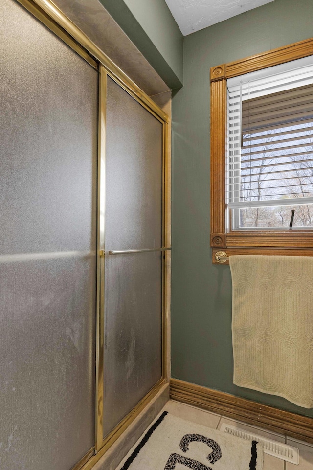 bathroom with tile patterned flooring, visible vents, a shower with shower door, and baseboards