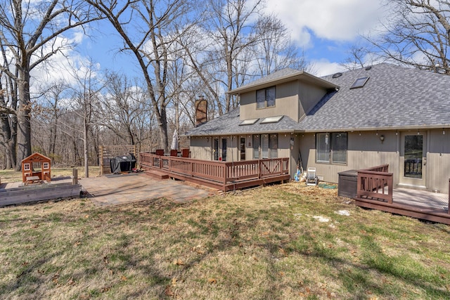 rear view of house featuring a yard, roof with shingles, a deck, and a chimney