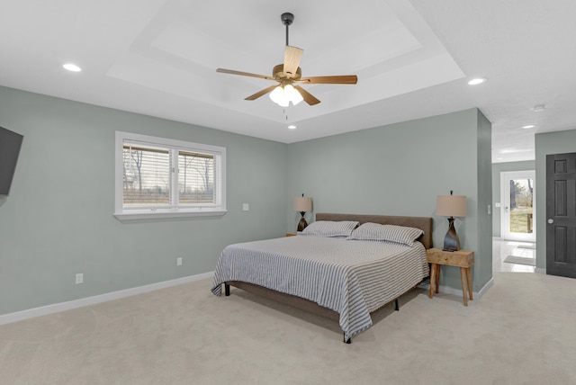 bedroom featuring a tray ceiling, baseboards, and carpet flooring