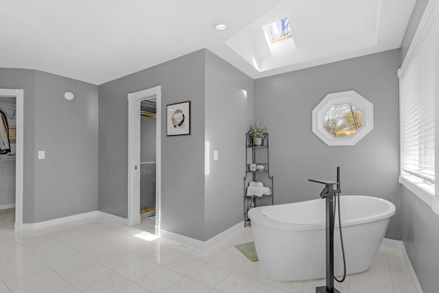 full bath with a freestanding tub, baseboards, and a skylight