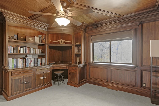 office space featuring ceiling fan, light colored carpet, wood walls, built in desk, and wooden ceiling