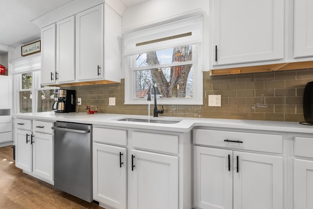 kitchen with a sink, light countertops, decorative backsplash, white cabinetry, and stainless steel dishwasher